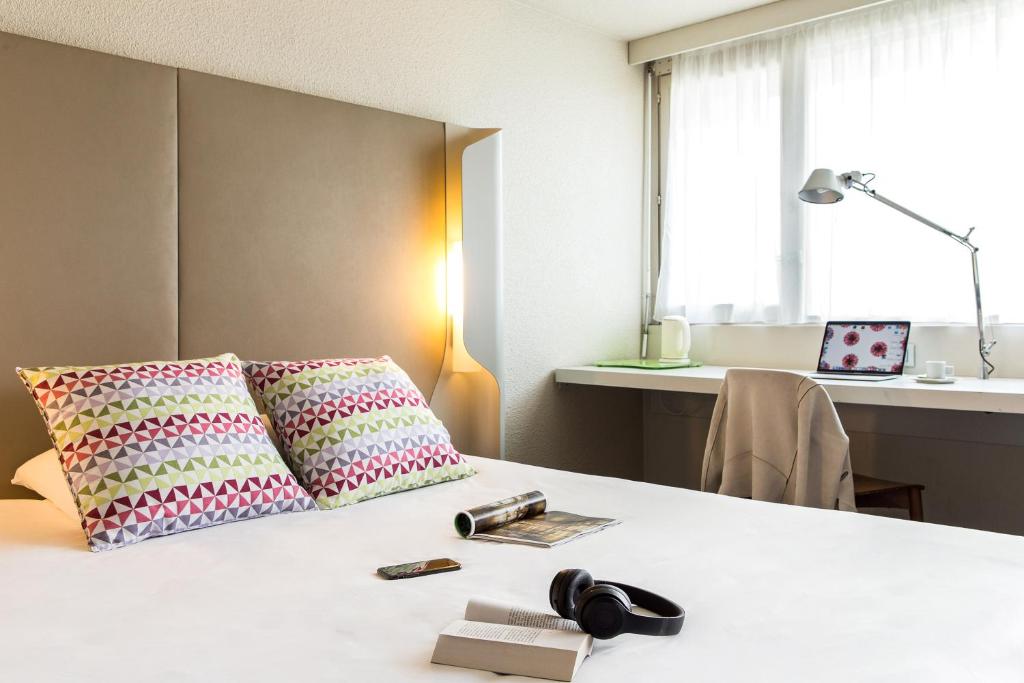 Zimmer mit einem Bett mit zwei Kissen und einem Schreibtisch in der Unterkunft Campanile Gueret in Guéret