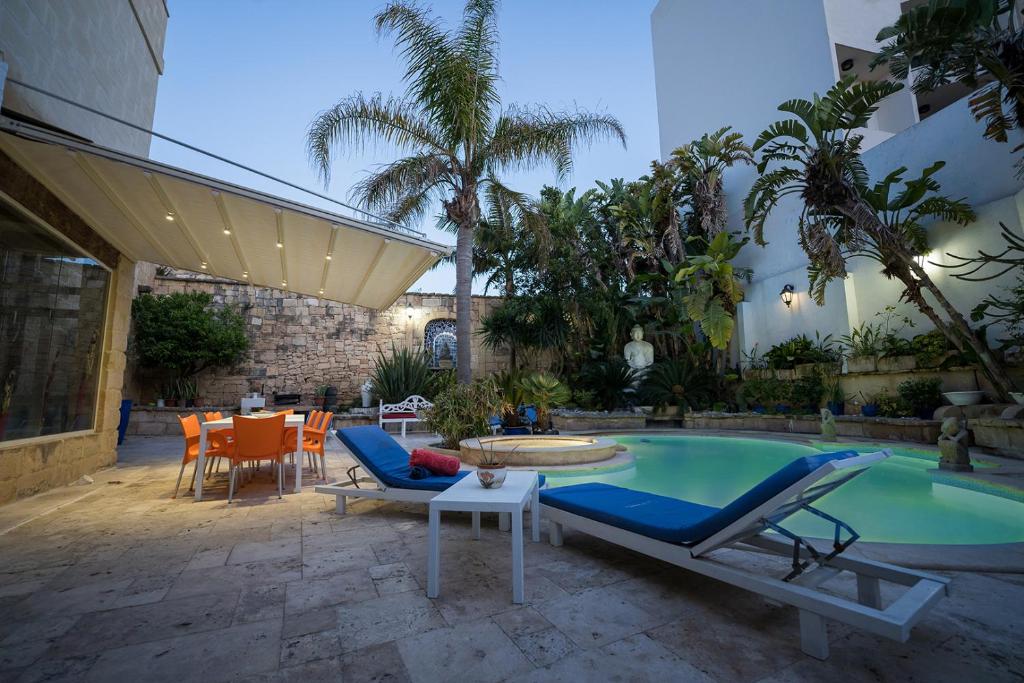 a patio with a pool and chairs and a table at Villa Buddha in Żurrieq