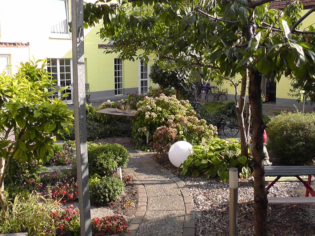 einen Garten mit einer Bank, einem Baum und Blumen in der Unterkunft Pension Elisabeth am Elberadweg in Prödel