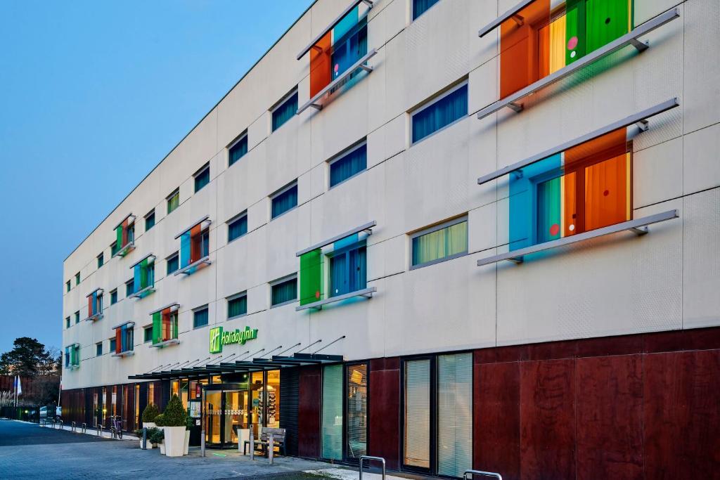 Holiday Inn Bordeaux Sud - Pessac, an IHG Hotel في بيساك: مبنى به نوافذ ملونة من الجانب