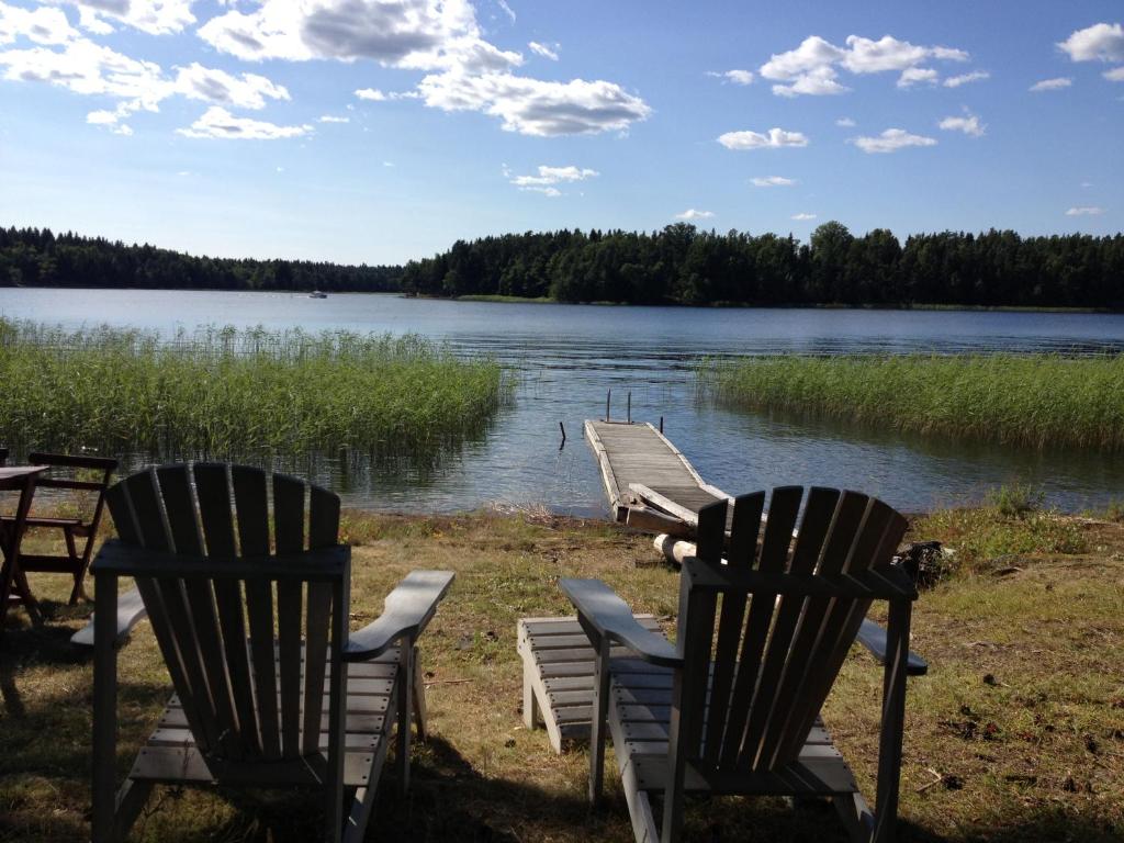 two chairs sitting next to a dock on a lake at SwedishCountryLiving / Skippers cottage in Köpmannebro