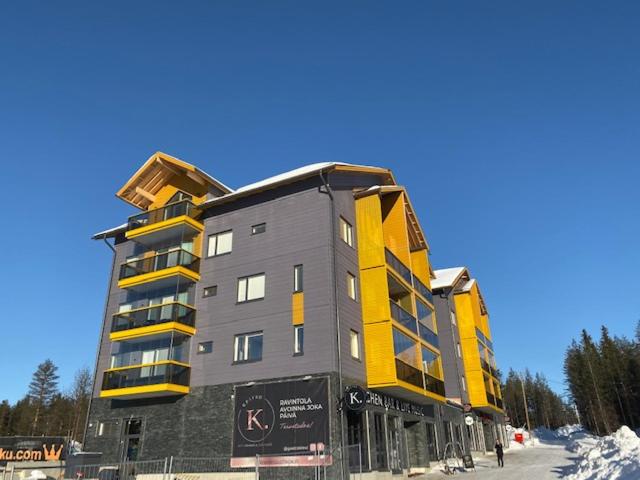 a large building with yellow and gray at Levin Kunkku B4 in Levi