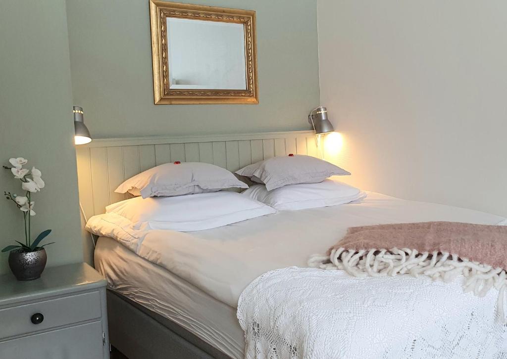 um quarto com uma cama com lençóis brancos e um espelho em Lofoten Home Apartment em Leknes