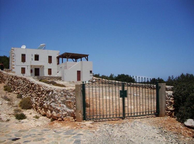 einen Zaun vor einem Gebäude neben einer Steinmauer in der Unterkunft Villa Kastri in Gavdos