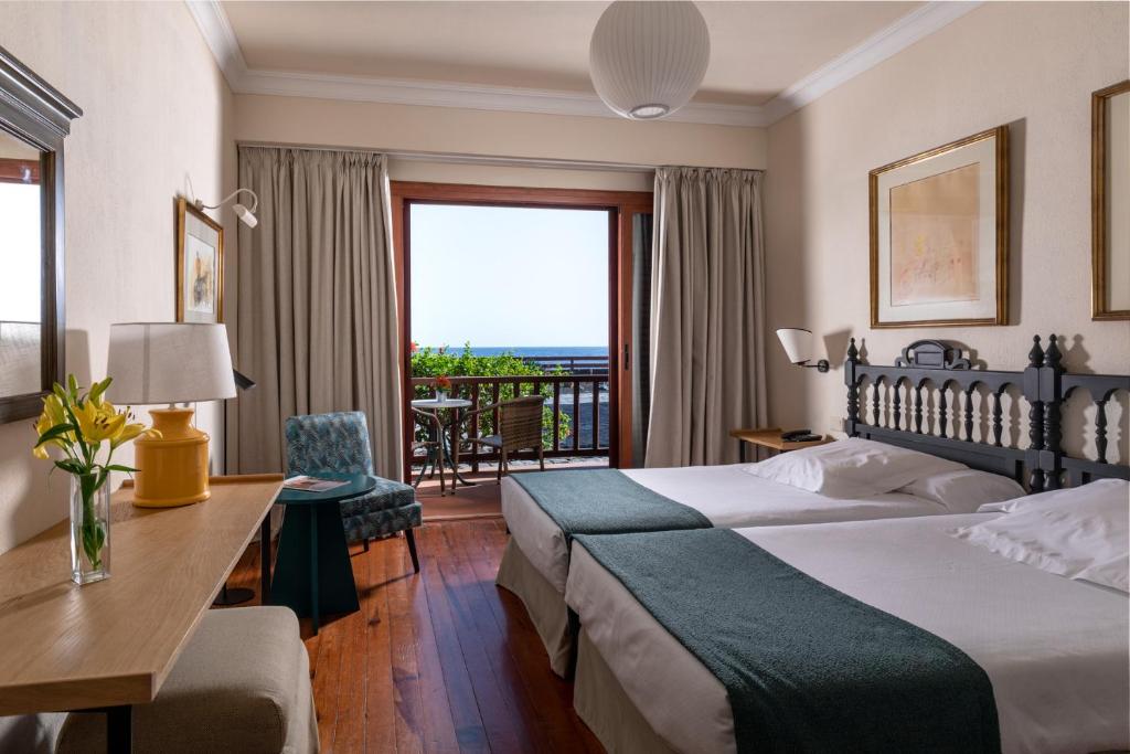 a hotel room with two beds and a desk and a balcony at Parador de El Hierro in Las Casas