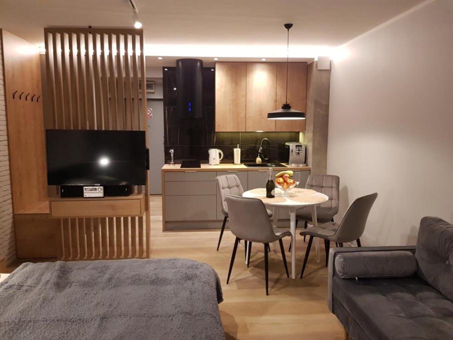 ein Wohnzimmer mit einem Tisch und einer Küche in der Unterkunft Apartament green-balcony z parkingiem i rowerami in Świnoujście