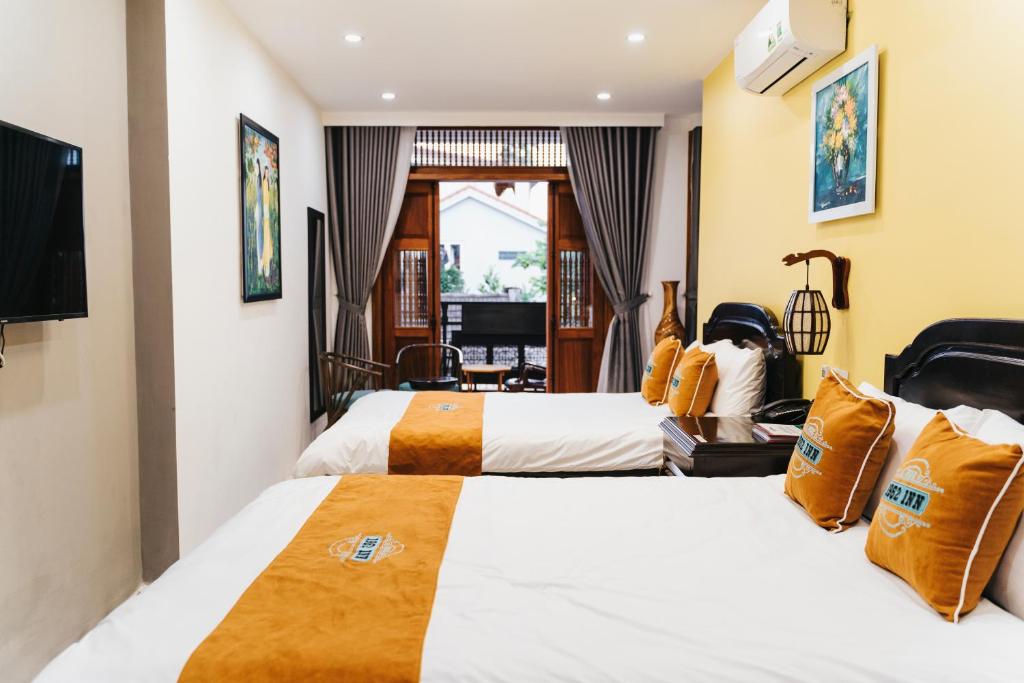 a hotel room with two beds and a television at Hue 1962 INN in Hue