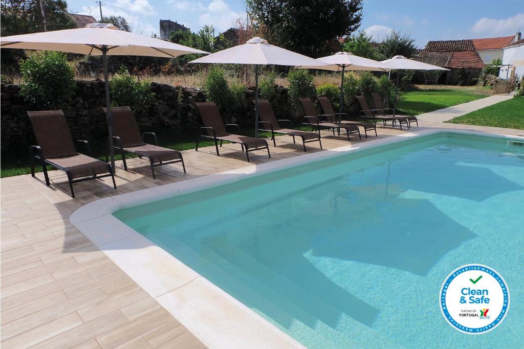 a blue swimming pool with chairs and umbrellas at Casa dos Edras in Miranda do Douro