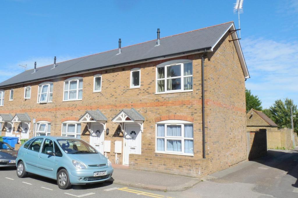 un coche azul estacionado frente a un edificio de ladrillo en Friars Walk houses with 2 bedrooms, 2 bathrooms, fast Wi-Fi and private parking, en Sittingbourne