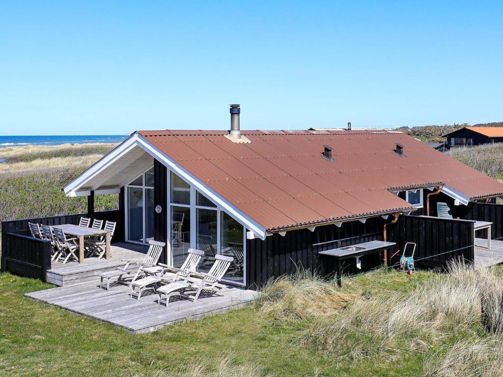una casa con terrazza con sedie e tavolo di 6 person holiday home in Hj rring a Lønstrup