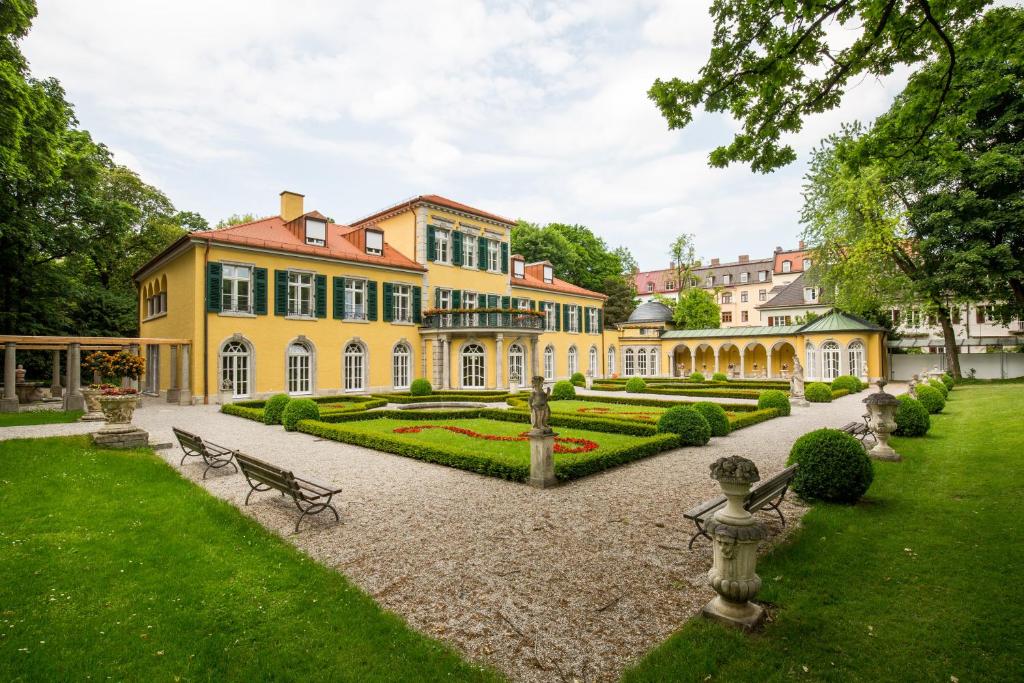 a large yellow house with a garden in front of it at Gästehaus der Katholischen Akademie in Bayern in Munich