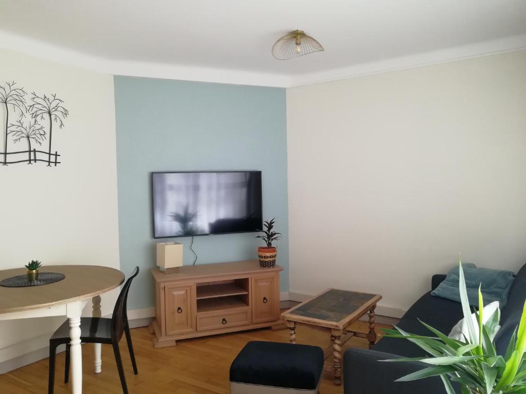 ein Wohnzimmer mit einem Sofa und einem TV in der Unterkunft L'Escale Fougeraise in Fougères