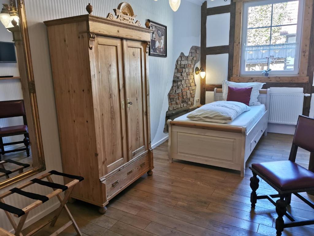 a bedroom with a bed and a large wooden cabinet at Hotel Mohrenbrunnen in Eisenberg