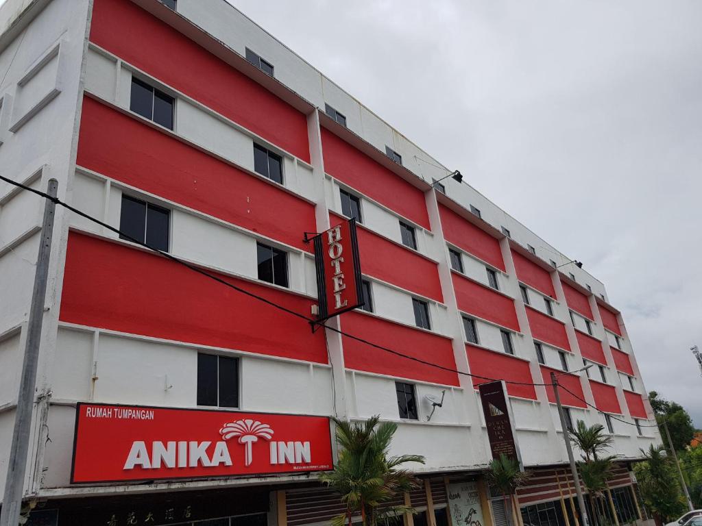 un edificio rojo y blanco con un cartel en él en Anika Inn - Kluang, en Keluang