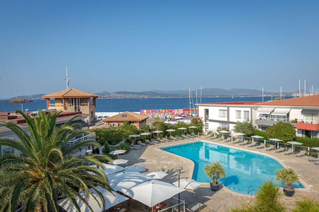 een groot zwembad met stoelen en een gebouw bij Best Western Plus La Marina in Saint-Raphaël