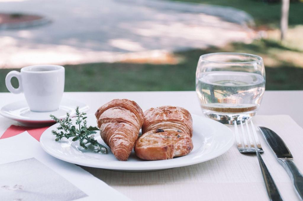 een bord croissants en een glas water op een tafel bij Best Western Hôtel des Thermes - Balaruc les Bains Sète in Balaruc-les-Bains