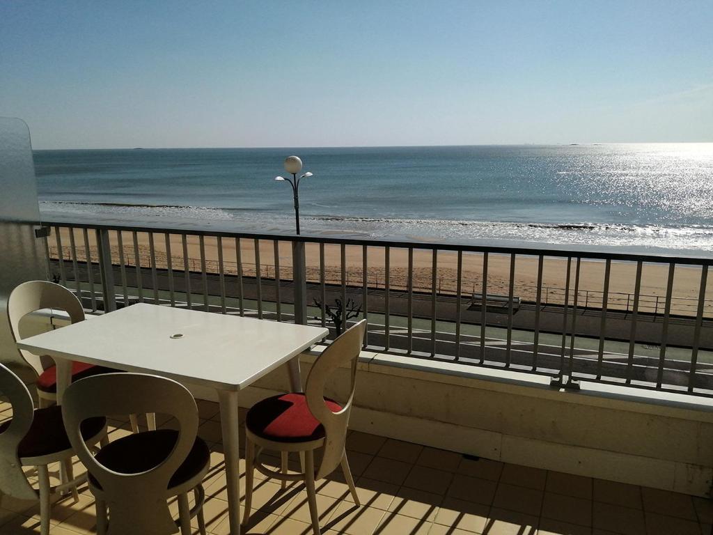 une table et des chaises sur un balcon avec la plage dans l'établissement Cap sur l'Océan pour 4 personnes, à La Baule