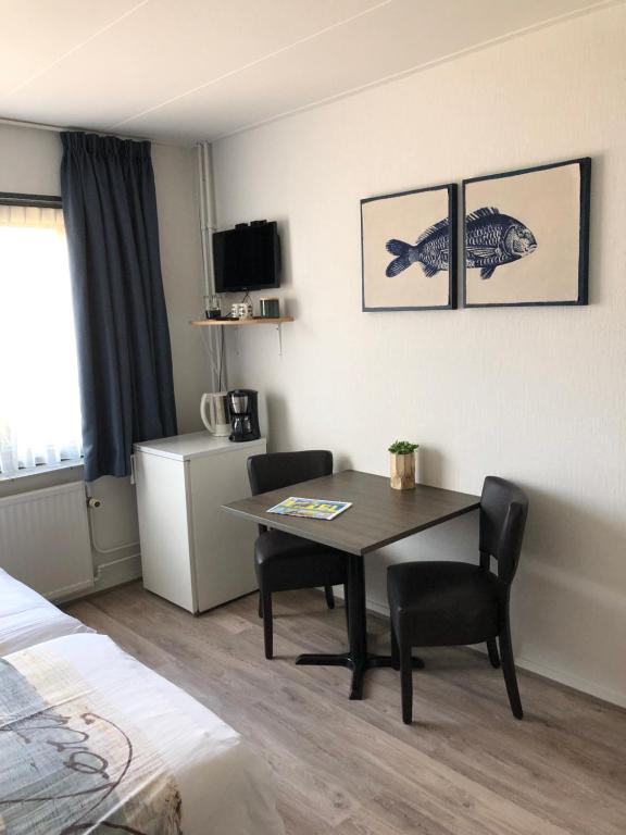 une chambre d'hôtel avec une table, des chaises et un lit dans l'établissement Pension Brinkvis, à De Koog
