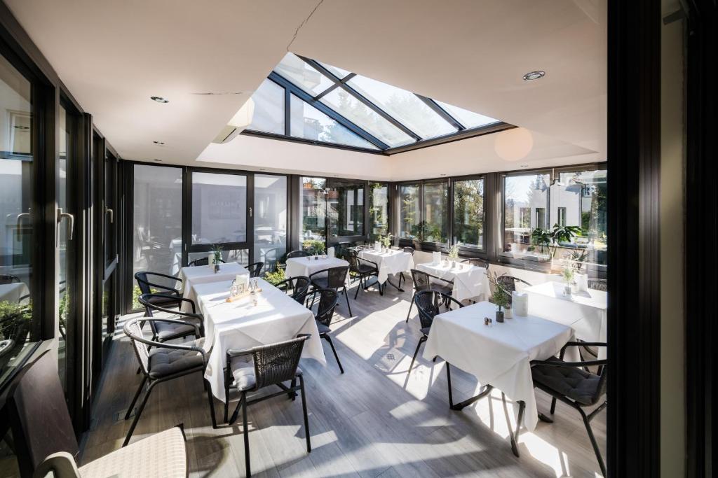 a restaurant with white tables and chairs and windows at Hotel Bella Vista in Konstanz