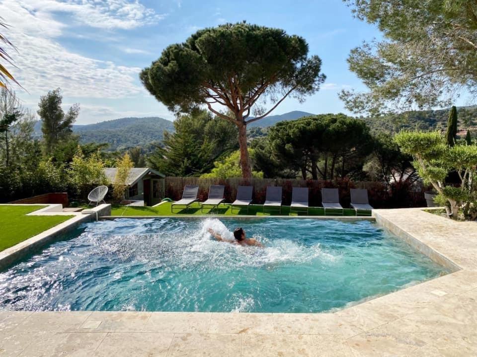 un uomo che nuota in una piscina in un cortile di HomeStay Bormes a Bormes-les-Mimosas