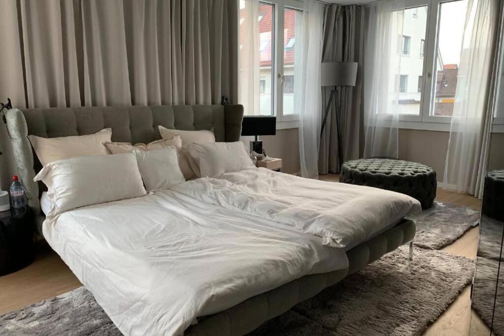 Luxury Penthouse Zurich في زيورخ: سرير أبيض كبير في غرفة بها نوافذ