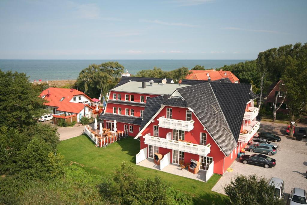 eine Luftansicht eines großen roten Hauses mit einem Parkplatz in der Unterkunft Strandhotel Deichgraf Graal-Müritz in Graal-Müritz