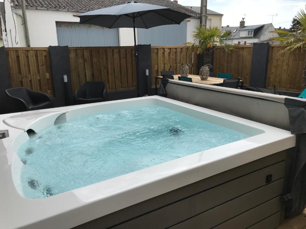 a hot tub in a backyard with an umbrella at la villa du clos avec "spa" in Cayeux-sur-Mer