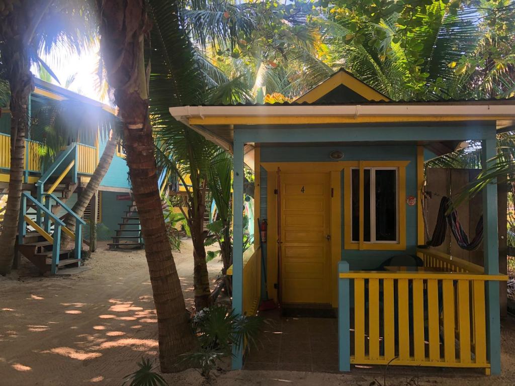a small house with a yellow door and palm trees at Colinda Cabanas in Caye Caulker