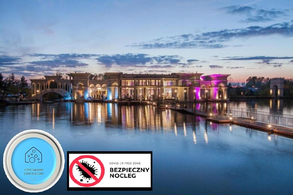 a building on the water with a sign in front of it at Hotel Venecia Palace in Michałowice