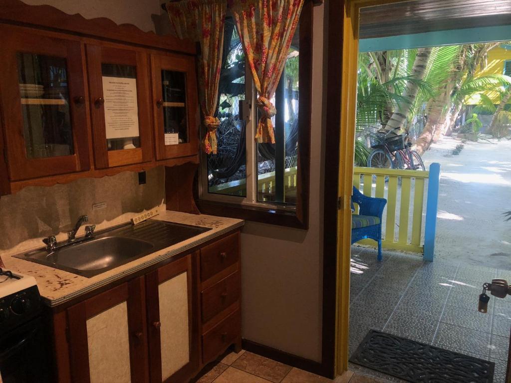 a kitchen with a sink and a door to a patio at Colinda Cabanas in Caye Caulker