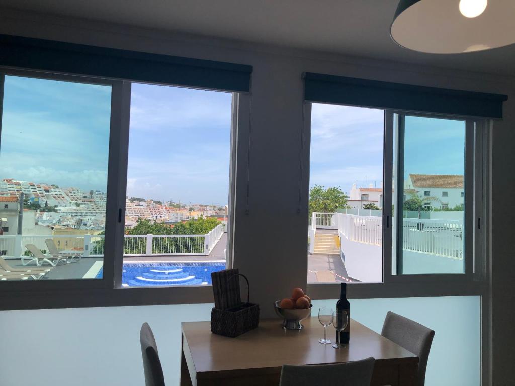 a dining room with a table and three windows at Bayview Apartment 106 in Albufeira