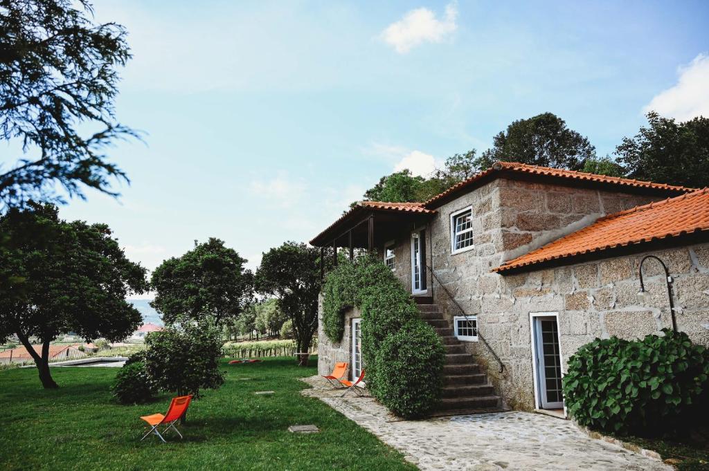 una casa de piedra con una silla roja en el patio en Casa do Xico en Guardizela