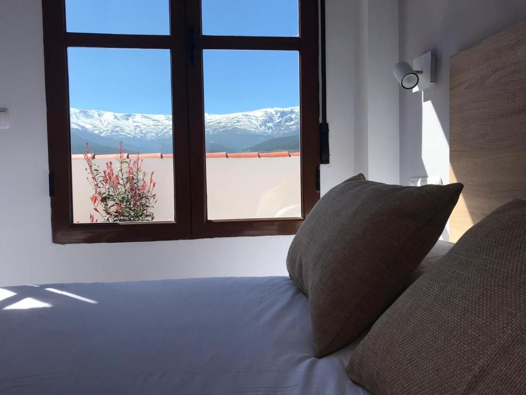 a bed with a window with a view of snow covered mountains at Hotel El Picón de Sierra Nevada in Jerez del Marquesado