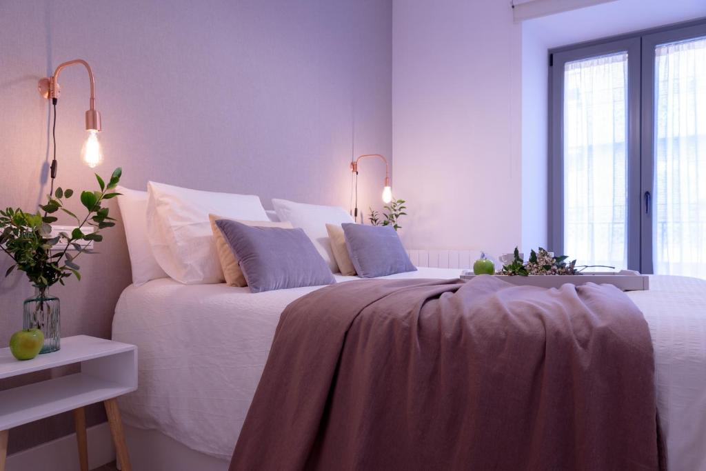 een slaapkamer met een groot bed met witte lakens en kussens bij FerAla Suites Centro A in Granada