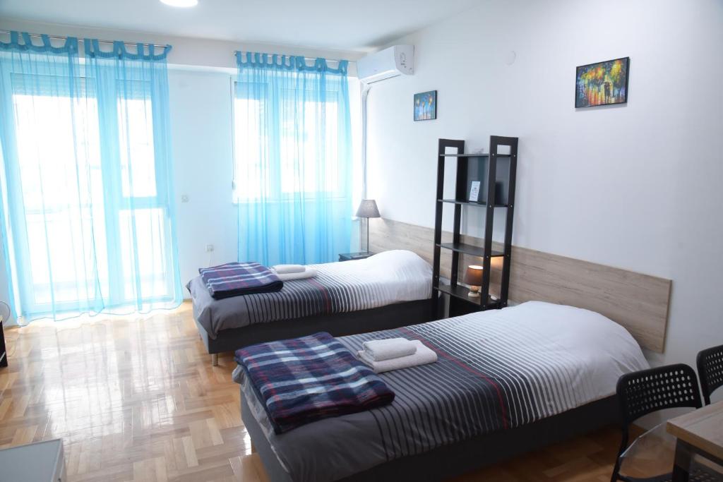 two beds in a room with windows and a table at Petrograd Apart. in Bitola