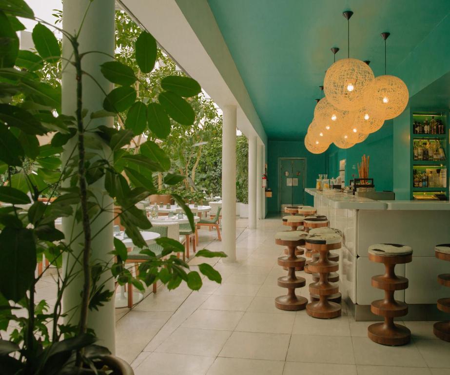 墨西哥城的住宿－Condesa df, Mexico City, a Member of Design Hotels，一间拥有绿色墙壁的餐厅以及一个带凳子的酒吧