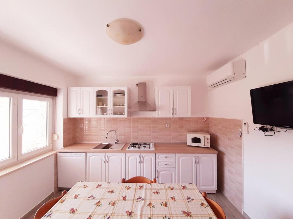 ツレスにあるApartments Renato Mužić Cresの白いキャビネットとテーブルと椅子のあるキッチン