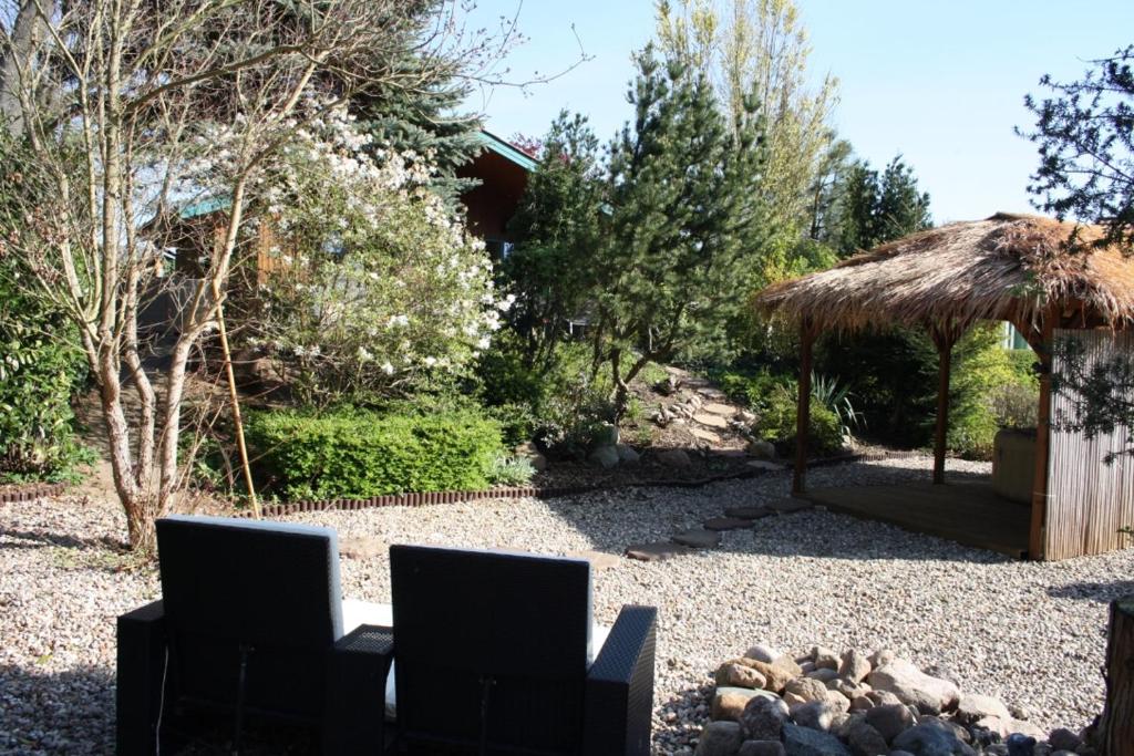 un jardín con 2 sillas y techo de paja en Ferienhaus SEE Romantik mit Sauna und Whirlpool, en Zislow