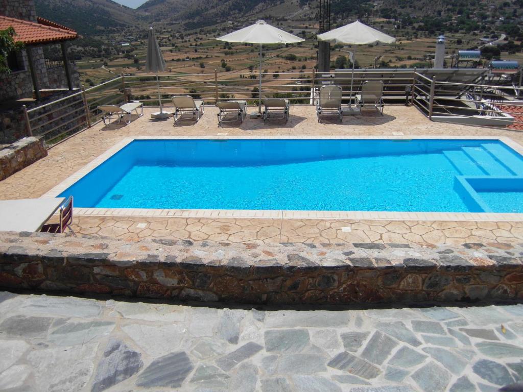 a large blue swimming pool with chairs and tables at Panorama Askifou in Karés