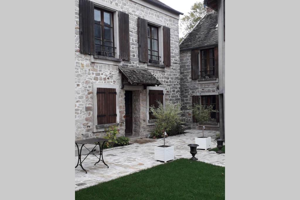 a courtyard of an old stone house with green grass at ARTEMIS GÎTE in Barbizon