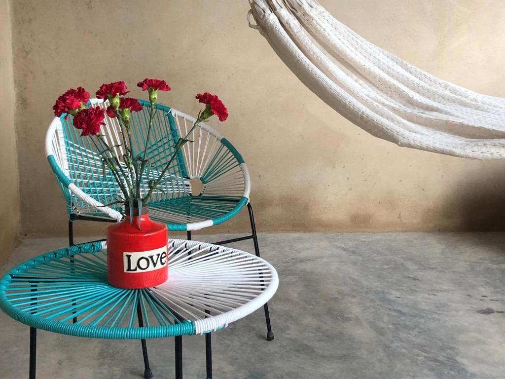 un jarrón con flores rojas en una mesa y dos sillas en Casa Naab, en Palenque
