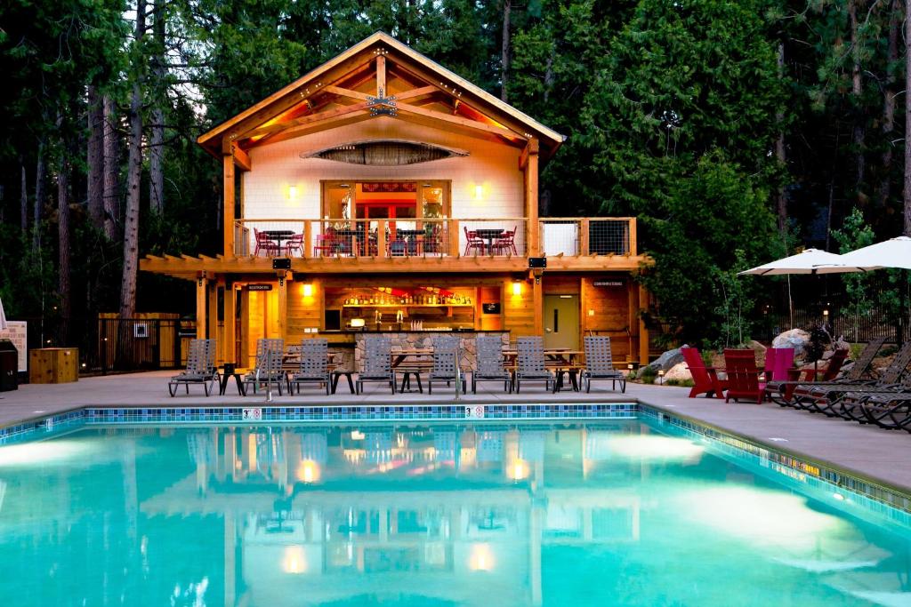 une cabane en rondins avec une piscine en face d'une maison dans l'établissement Evergreen Lodge at Yosemite, à Groveland