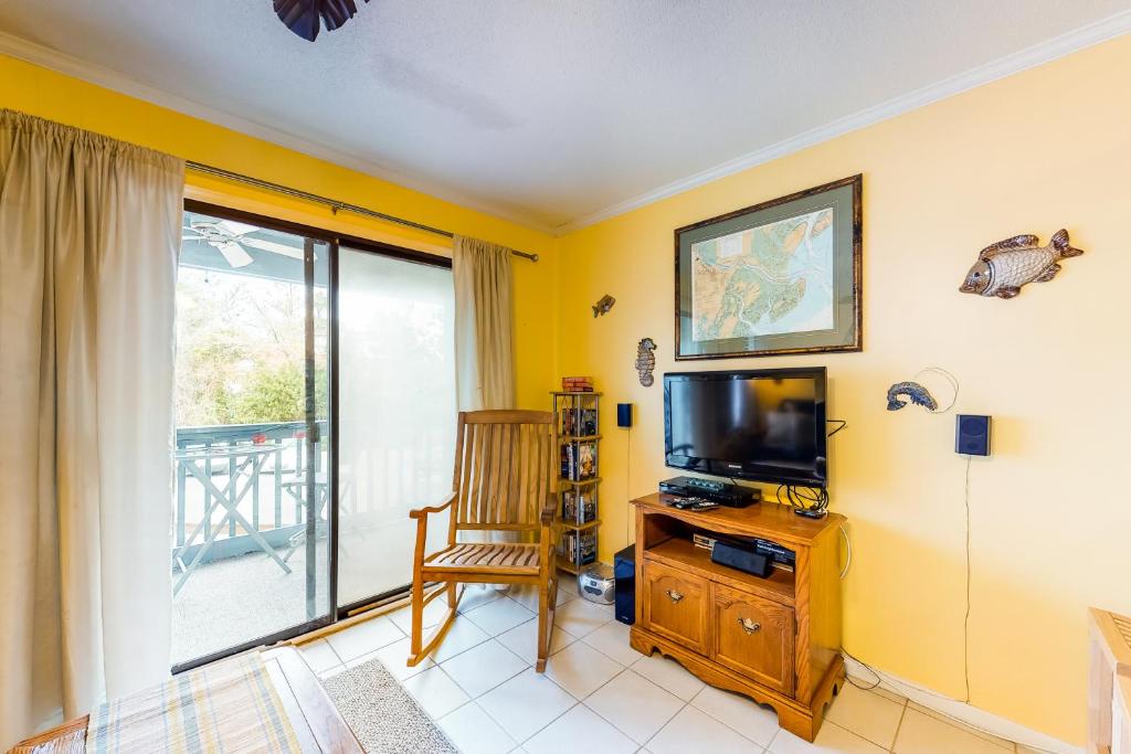 a living room with a television and a balcony at As You Wish in Tybee Island