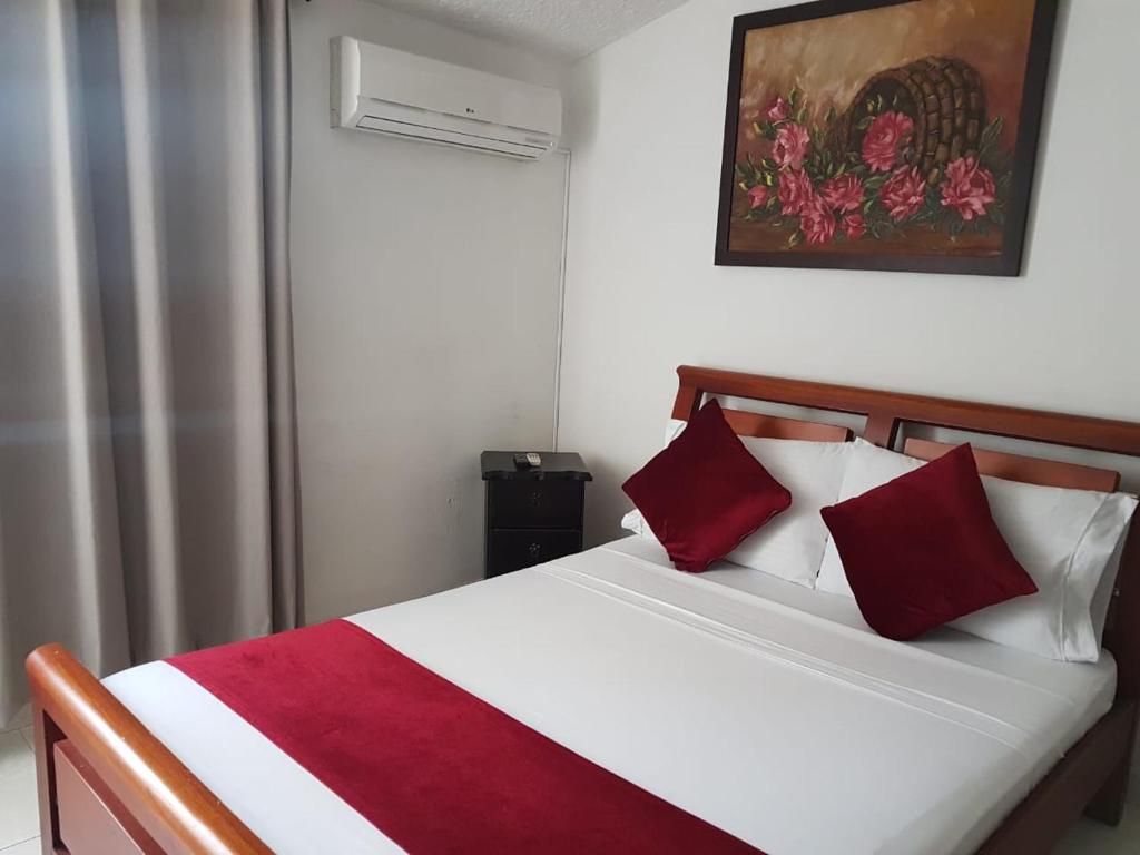 Schlafzimmer mit einem Bett mit roten und weißen Kissen in der Unterkunft Hotel Don Juan Colonial in Floridablanca