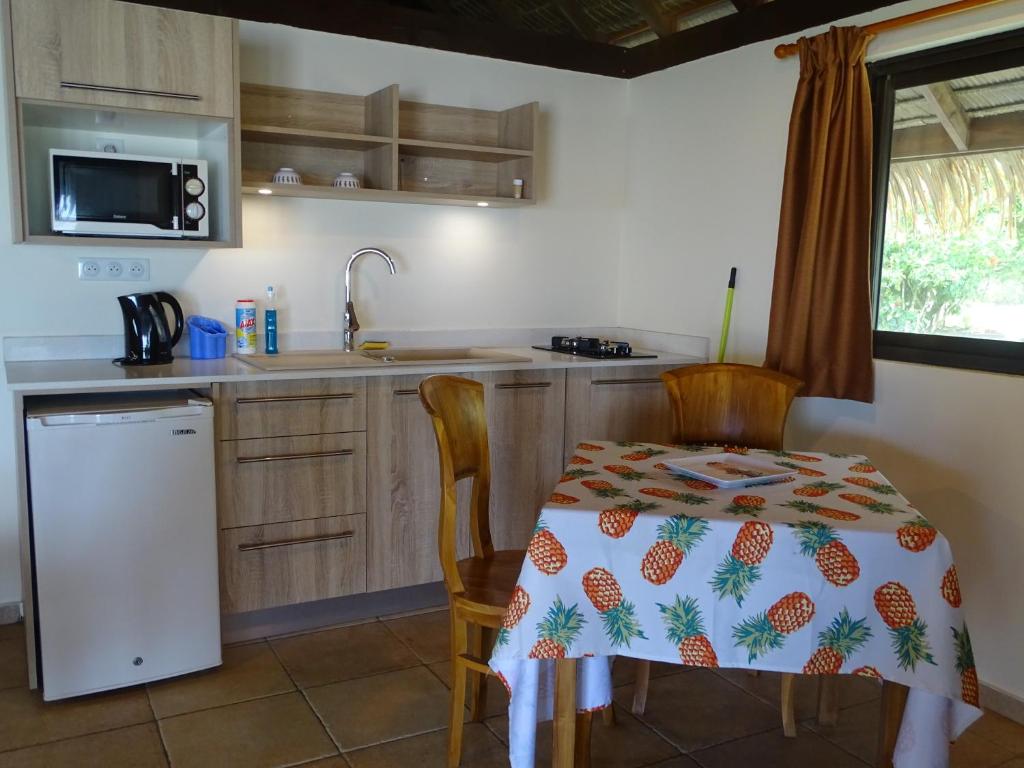 a kitchen with a table and chairs and a sink at Hôtel Atiapiti in Opoa