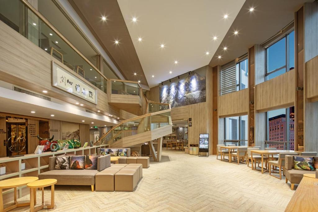 a lobby with a staircase and tables and chairs at Atour Hotel Xi'an Gaoxin Branch in Xi'an