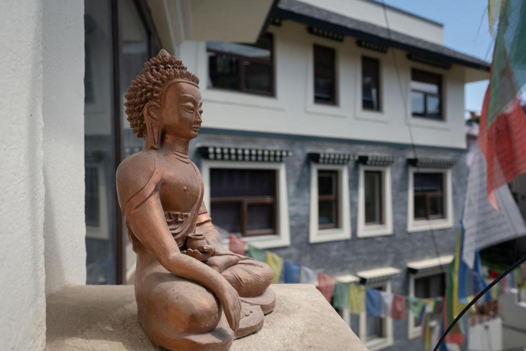 ViaVia Boutique Hotel - Kathmandu في كاتماندو: تمثال لامرأة جالسة على حافة مبنى