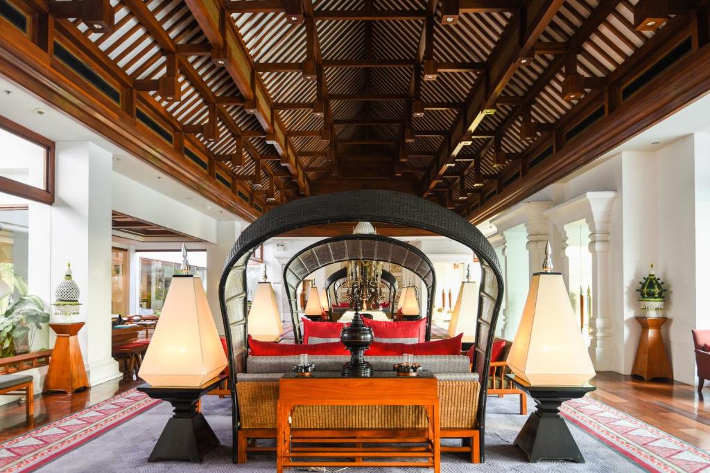 An ornate open-sided lounge with rattan seating beneath a dramatic timber ceiling.