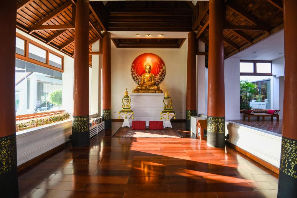 A bright open hall centers on a Buddhist shrine beneath a timbered roof.