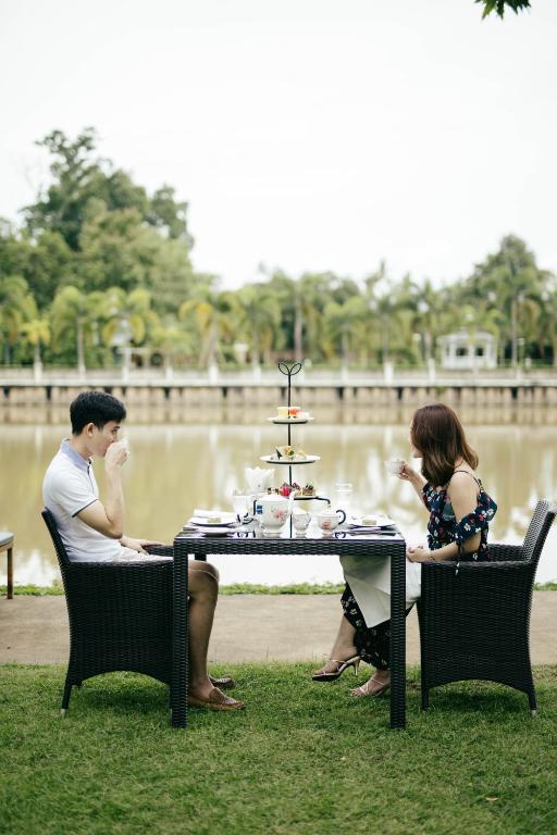 Two guests dining at a riverside table on the hotel grounds.